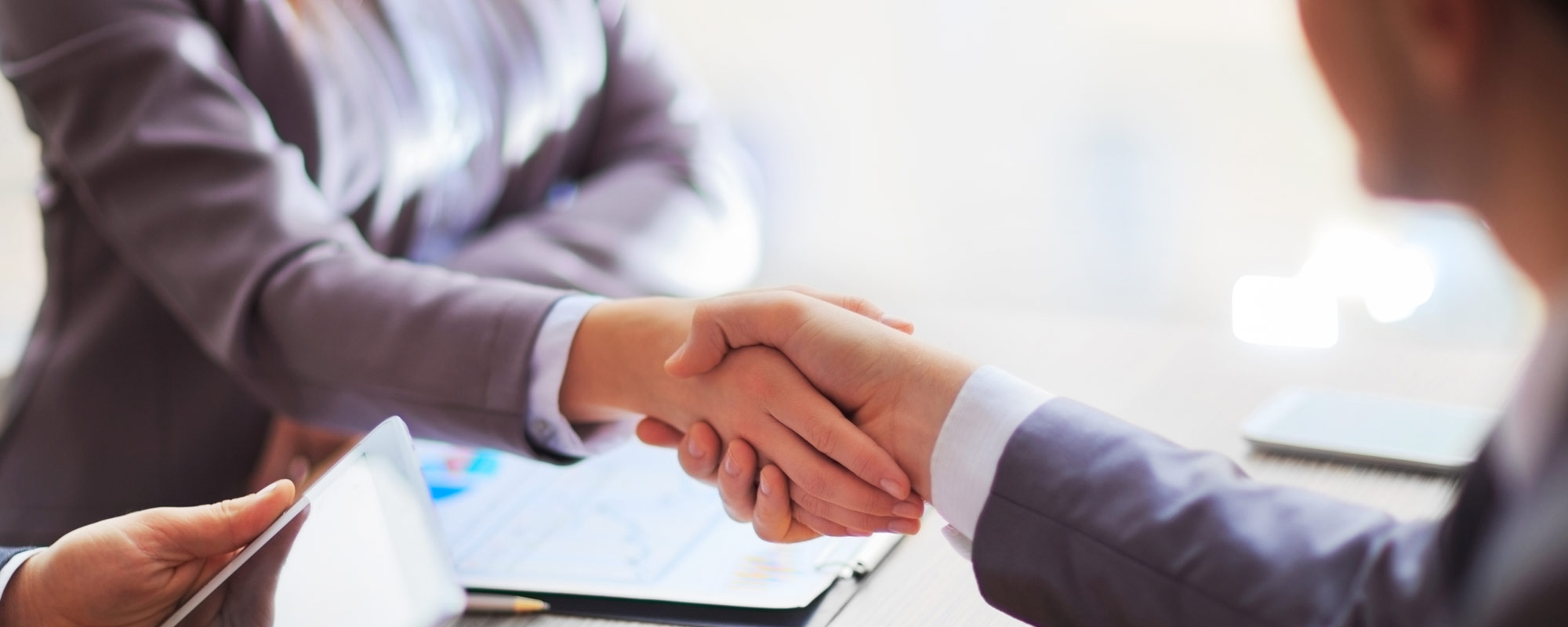 An insurance broker and a commercial client shaking hands.